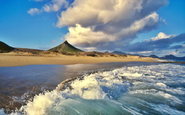 Blick entlang des goldenen Sandstrandes